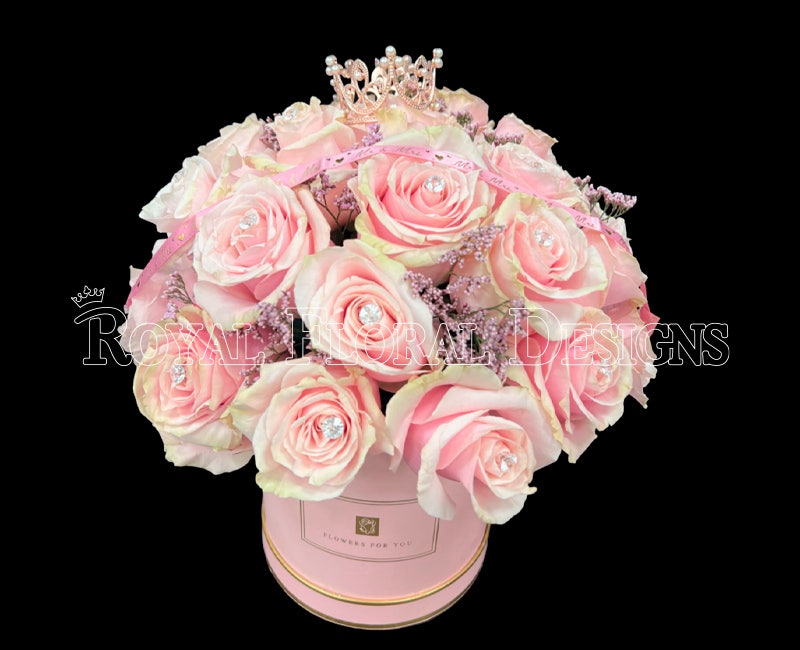 Blush pink roses arranged in a signature Royal Floral Designs hat box, crowned with a tiara