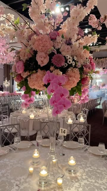 Elevated blush floral centerpiece with candlelight on a sweet sixteen reception table by Royal Floral Designs