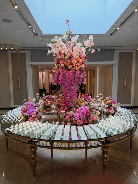 Vibrant pink cascading floral centerpiece on a mirrored escort-card table at a mitzvah celebration by Royal Floral Designs