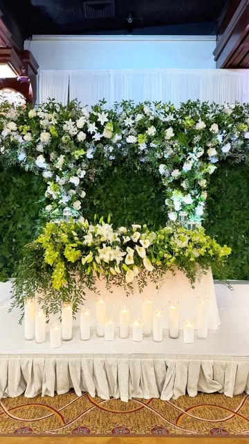 White and green floral sweetheart-table backdrop with candles at a wedding designed by Royal Floral Designs